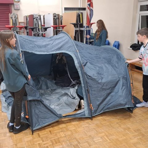 Scouts tensioning a newly pitched tunnel tent during their troop meeting