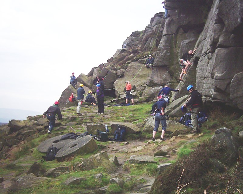 Explorer Scouts in helmets rock climbing on a gritstone edge